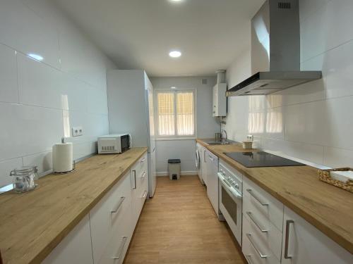 a kitchen with white cabinets and a wooden counter top at Sánchez Home in Sanlúcar de Barrameda