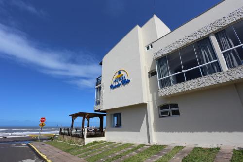 a white building with the ocean in the background at Pousada Praia Do Meio in Torres