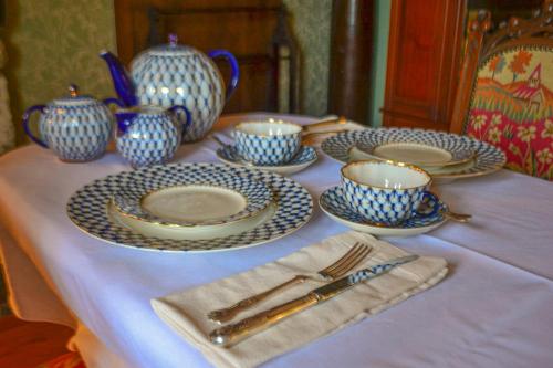 The Lady Maxwell Room at Buittle Castle في دالبيتي: طاولة عليها صحون و مزهريات زرقاء و بيضاء