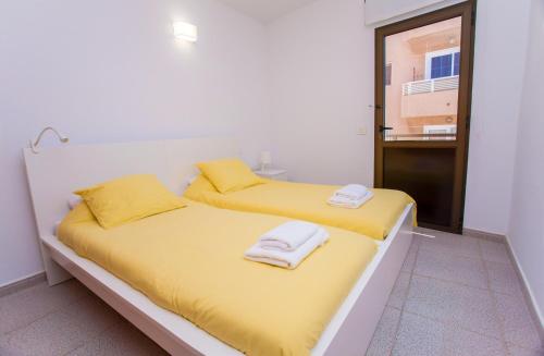 two beds in a room with yellow sheets and towels at Arinaga Colors, tu casa en la playa in Arinaga
