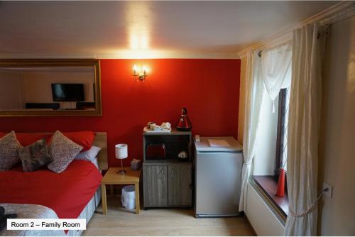 1 dormitorio con paredes rojas, 1 cama y 1 mesa en Pentre Riding Stables en Abercraf