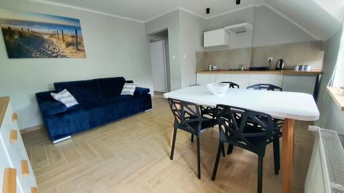 a living room with a table and a blue couch at Pod Żaglami in Dąbki