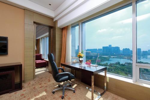 a hotel room with a desk and a large window at Crowne Plaza Nanjing Jiangning by IHG in Nanjing