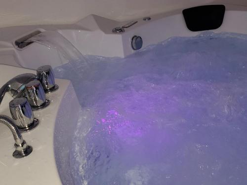 una vasca da bagno riempita con acqua viola in un lavandino di LE PIED A TERRE a La Châtre