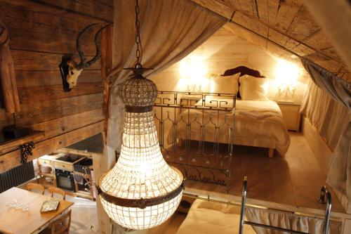 Habitación con cama y lámpara de araña grande. en L'annexe du chateau des Girards, en Lans-en-Vercors