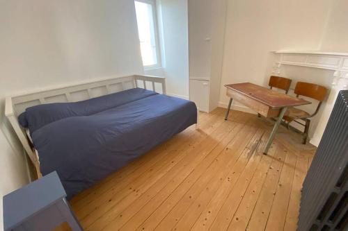 um quarto com uma cama e uma mesa de madeira em Appartement lumineux Cancale, 80m2, 3 chambres. em Cancale