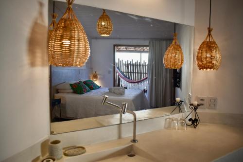 ein Badezimmer mit einem Waschbecken und einem Spiegel mit einem Bett in der Unterkunft Pousada Tartaruga in Pipa