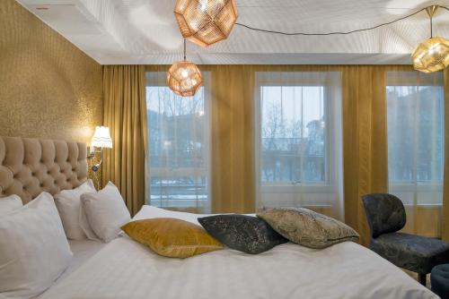 a bedroom with a white bed with pillows and windows at Best Western Hotel Akersberga in Åkersberga