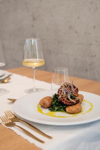a plate of food on a table with a glass of wine at Borralha Hotel, Restaurante & Spa in Vila Real