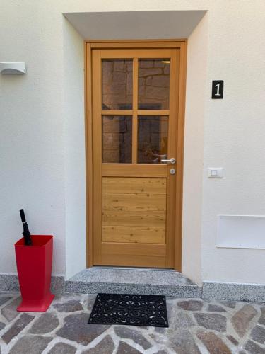 eine Holztür auf einem Gebäude mit einem roten Eimer in der Unterkunft Casa al Sole Apt 1 in Pinzolo