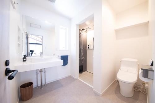 a white bathroom with a sink and a toilet at Cherrywoods Place by Hakuba White Fox Company in Hakuba