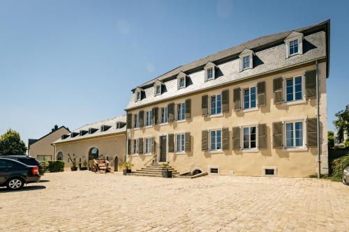 un grand bâtiment avec une voiture garée dans une allée dans l'établissement Restauberge Peitry, à Roodt-sur-Syre