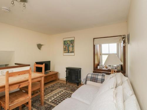 a living room with a white couch and a television at Grouse Cottage in Newtonmore