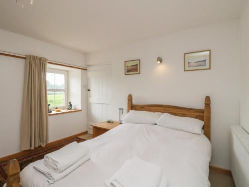a bedroom with a white bed and a window at Osprey Cottage in Newtonmore