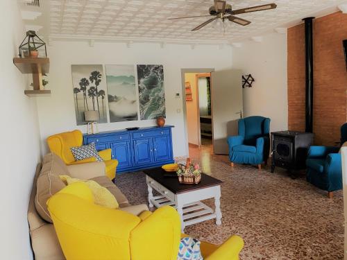 a living room with yellow furniture and blue chairs at El Balcón de la Colgada in Ossa de Montiel
