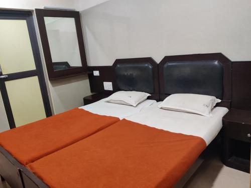 a bedroom with a large bed with an orange blanket at Hotel Sarada Nivas in Chennai