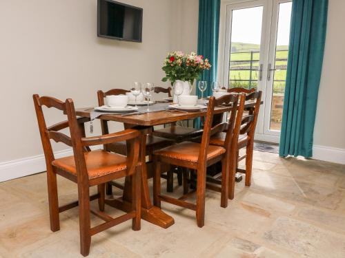 a wooden dining room table and chairs with flowers on it at White Lea in Richmond