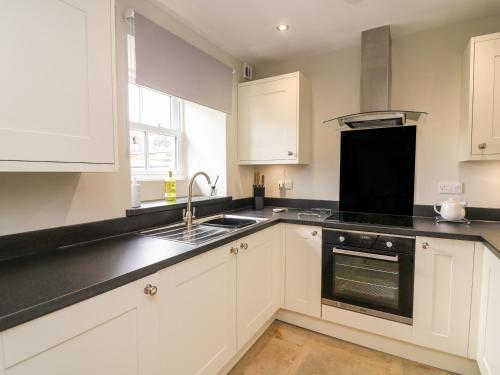 a kitchen with white cabinets and black counter tops at White Lea in Richmond