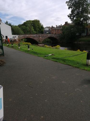 a road next to a river with a bridge at Lake District and Eden Valley Thornhill Lodge in Long Marton