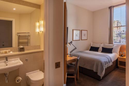 um quarto de hotel com uma cama e um lavatório em The Resident Kensington em Londres