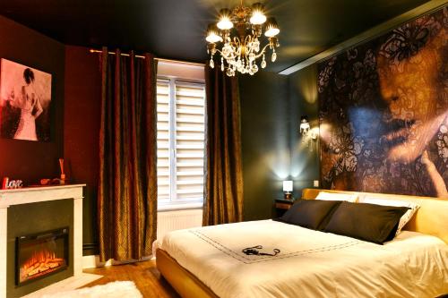 a bedroom with a bed with a fireplace and a chandelier at MoonLOVE, SPA/Sauna et Jacuzzi privés, charme et détente. in Nancy