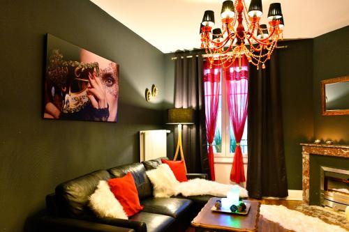 a living room with a leather couch and a chandelier at MoonLOVE, SPA/Sauna et Jacuzzi privés, charme et détente. in Nancy