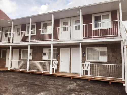 a apartment building with two chairs on the porch at Auberge Motel LA RÉFÉRENCE in Trois-Rivières