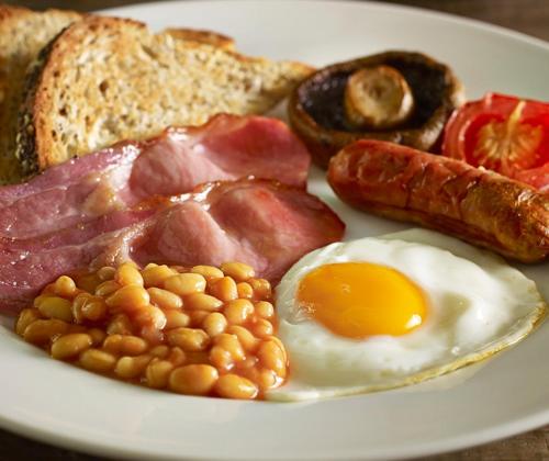 a plate of breakfast food with eggs bacon beans and toast at The Churchill By Greene King Inns in Royal Wootton Bassett