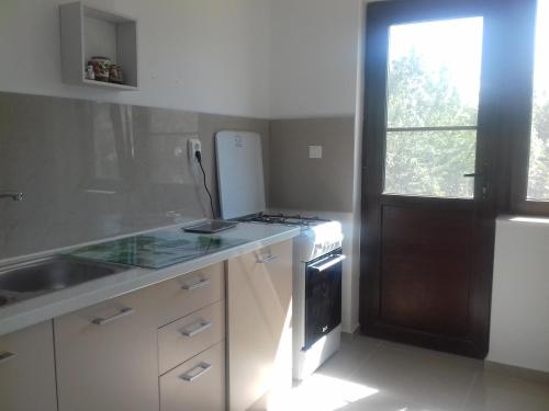 uma cozinha com um fogão, um lavatório e uma janela em PENSIUNEA AGROTURISTICĂ ANGHELIKI em Tulcea