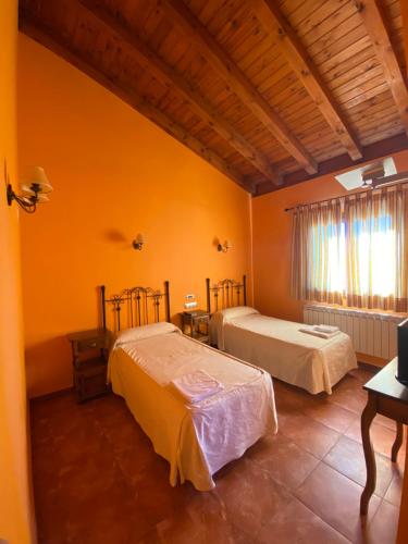 2 camas en una habitación con paredes de color naranja en Hotel Hostería de Monzón, en Monzón de Campos