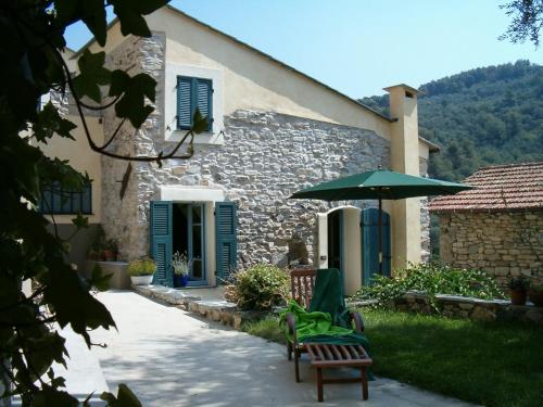 une maison en pierre avec 2 chaises et un parasol dans l'établissement I Freschi, à San Bartolomeo al Mare