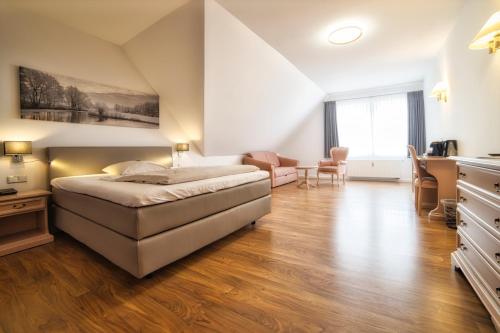 a bedroom with a bed and a desk and chairs at Golfhotel Wagenfeld in Wagenfeld