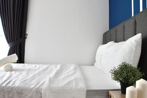 a bedroom with a bed with white sheets and pillows at Bell Suites @ Sunsuria City in Sepang