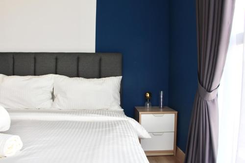 a bedroom with a bed with blue walls and a window at Bell Suites @ Sunsuria City in Sepang