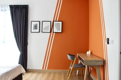 a bedroom with orange walls and a table and a bed at Bell Suites @ Sunsuria City in Sepang