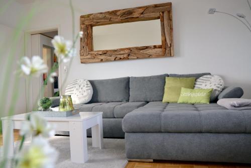 ein Wohnzimmer mit einem grauen Sofa und einem Spiegel in der Unterkunft Lakeview Penthouse in Meersburg
