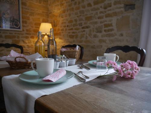 una mesa con platos, tazas y flores. en Le Tamaris Chambres d'hôtes, en Sainte-Hermine