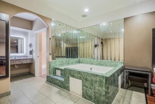 un ampio bagno con vasca e specchio di Scottish Inns & Suites IAH Airport-Beltway 8 a Houston