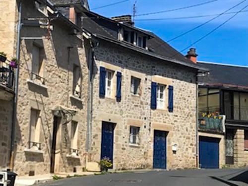 an old stone building with blue doors on a street at Vue sur la Vezere in Treignac