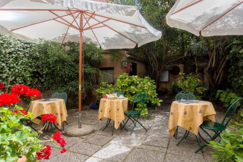 two tables and chairs with an umbrella and flowers at Casa Mimma in Venice