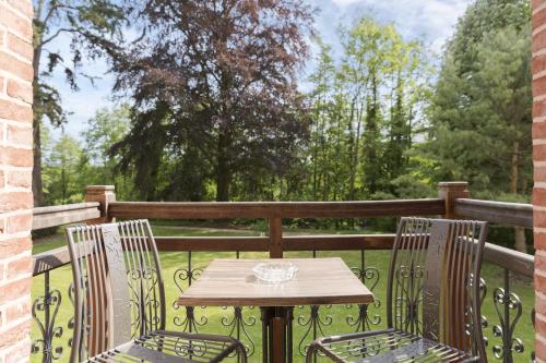 a wooden table and two chairs on a balcony at Belle Isle Sur Risle - Chateau Hotel & Spa in Pont-Audemer