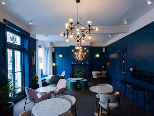 ein blaues Zimmer mit Tischen, Stühlen und einem Kronleuchter in der Unterkunft The Masons Arms Hotel in Louth