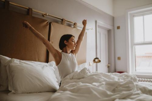 Una mujer acostada en la cama con sus brazos en el aire en The Masons Arms Hotel, en Louth