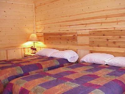 two beds in a room with wooden walls at The Bull Moose Lodge in Alpine