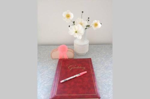 a red notebook with a pen and a vase of flowers at Sundbyvestervarehus in Copenhagen