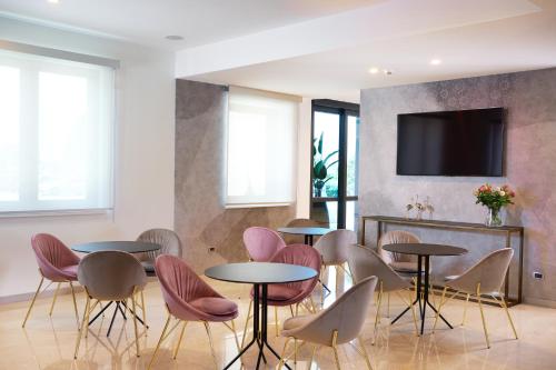 una sala con tavoli, sedie e TV di Hotel Omnia a Noventa di Piave