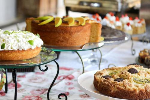 een tafel met daarop drie taarten op schalen bij Hotel Fazenda Casarão do Vale in Massaranduba