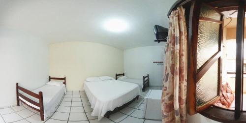 um pequeno quarto com 2 camas e uma janela em Hotel Praia Grande em Penha