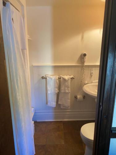 a bathroom with a toilet and a sink and towels at The Olde Angel Inn in Niagara on the Lake
