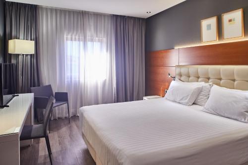 
a hotel room with a large bed and two lamps at Hotel Silken Amara Plaza in San Sebastián
